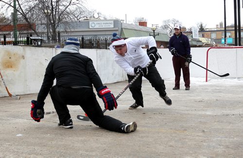 RUTH BONNEVILLE / WINNIPEG FREE PRESS

Justin Maeren (middle) takes a shot into the net past Tyler Kee while Austin Goncalves (rear) looks on during a practice round of street hockey just before the start of the 3rd annual Village Winter Classic street hockey festival on Stradbook Ave. Saturday.  Stradbrook Ave. is closed to traffic until after 8pm this evening.  
Standup photo 


 Jan 28, 2017