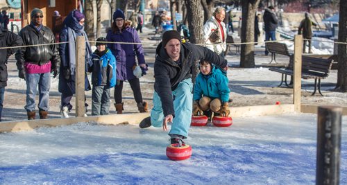 MIKE DEAL / WINNIPEG FREE PRESS
Clayton Salkeld throws a curling rock while his son Ollie, 8, watches during a game of Croki-curl with his family at The Forks Sunday afternoon.
For 49.8 piece on Crokinole.
170129 - Sunday, January 29, 2017.