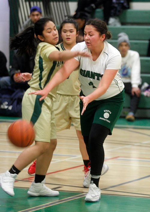 PHIL HOSSACK / WINNIPEG FREE PRESS  - Elmwood Giant #4 Alyia Klassen passes under the grasp of Tec Voc Hornet #8 Lheana Feliciano Hornet #7 Maria Pascual watches from behind, wednesday night as the two AAAA teams met at Elmwood High School. AGATE PAGE. - February 1, 2017