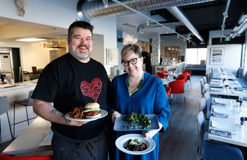 WAYNE GLOWACKI / WINNIPEG FREE PRESS

Restaurant Review. Chef Alexander Svenne holds a Burger with Tomato Jam and Bone Marrow Butter beside co-owner (wife) Danielle Carignan Svenne holding Duck Livers with fig and port and a dish of Grilled  Rapini at the Bouchée Boucher on Tache Ave.  Alison Gillmor story Feb. 14  2017