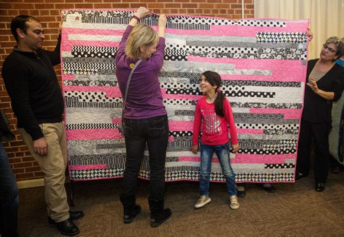 MIKE DEAL / WINNIPEG FREE PRESS
With her dad Khaled Ali (left), Zainab, 8, thanks Heather Glaser (centre) the person who made the quilt that was given to her. Heather is a member of The Riverview Quilters, a group of quilters who decided a year ago to make a quilt for each of thirteen Syrian refugees (three families) sponsored by the South Osborne Syrian Refugee Initiative. During a ceremony at the Churchill Park United Church everyone was presented with their handmade quilts.
170305 - Sunday, March 05, 2017.