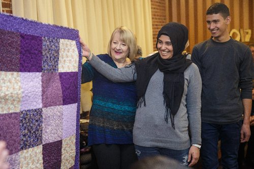 MIKE DEAL / WINNIPEG FREE PRESS
Tiba Al Abdallah (centre) and her brother Barakat Al Abdallah (right) look at a quilt as it is presented to her by Gladys Stoesz-Hammond (left) who is a member of The Riverview Quilters, a group of quilters who decided a year ago to make a quilt for each of thirteen Syrian refugees (three families) sponsored by the South Osborne Syrian Refugee Initiative. During a ceremony at the Churchill Park United Church everyone was presented with their handmade quilts.
170305 - Sunday, March 05, 2017.