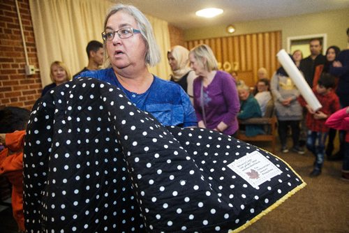 MIKE DEAL / WINNIPEG FREE PRESS
Riverview Quilter Trudy Mattey holds up a quilt to show the special tag that was put onto it. Trudy and the other members of The Riverview Quilters decided a year ago to make a quilt for each of the thirteen Syrian refugees (three families) sponsored by the South Osborne Syrian Refugee Initiative. During a ceremony at the Churchill Park United Church everyone was presented with their handmade quilts.
170305 - Sunday, March 05, 2017.