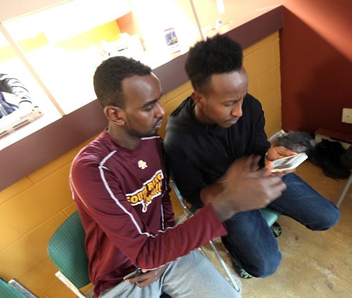 PHIL HOSSACK / WINNIPEG FREE PRESS  - Hurry up and wait -  Somalian Asylum seekers Liibaan Nur (left) and Ismail Mohamed check my iPhone to see if they recognize another man from Nigeria I photographed crossing the border. They knew him at the shelter but not before. Melissa Martin story.  -  March 3, 2017