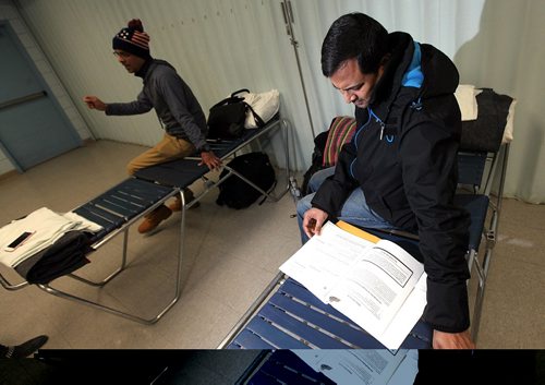 PHIL HOSSACK / WINNIPEG FREE PRESS  - Hurry up and wait - Hossain Shahadat  (left) and  Subir Barman spend time waiting at their Salvation Army overflow sleeping quarters. Subir studies the papers he filed with immigration earlier in the day. This area is normally part of a dining room.Melissa Martin story.  -  March 3, 2017