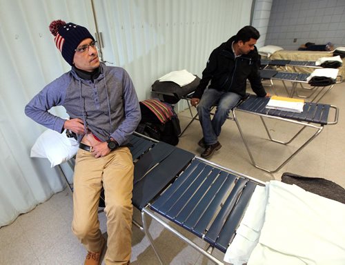 PHIL HOSSACK / WINNIPEG FREE PRESS  - Hurry up and wait - Hossain Shahadat  (left) shows us his scar from a stabbing attack  Subir Barman reads documents  at their Salvation Army overflow sleeping quarters. This area is normally part of a dining room.Melissa Martin story.  -  March 3, 2017