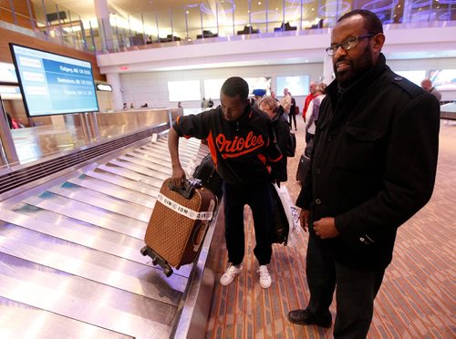 PHIL HOSSACK / WINNIPEG FREE PRESS  -  Abdirashid Abukar Mohamed picks his possesions up off the luggage carousel at Richardson International Tuesday evning as hi uncle Abdi Ismail (right) watches. See Carol Sanders story.  -  March 21, 2017