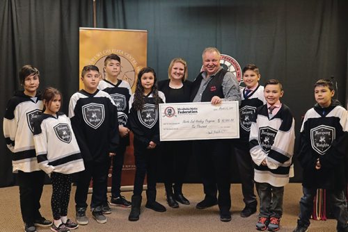 Canstar Community News Dana Riccio (middle, left) and president of the Manitoba Metis Federation David Chartrand (middle, right) and the Norquay Knight hockey player at the cheque presentation on Mar. 23, 2017.