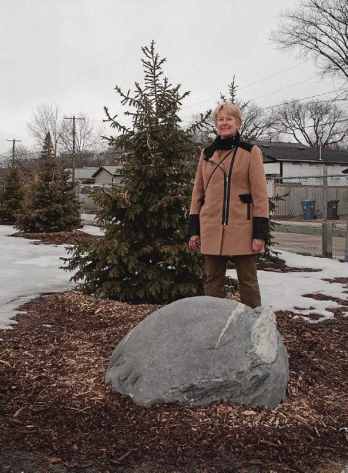 Canstar Community News March 27, 2017 - Christine Frank, chair and committee member of the Wayoata School Greening Project, poses next to a rock from Churchill, Man., and a stand of fir trees that were planted in the fall of 2016 in the first phase of a major greening project the school is undertaking. (SHELDON BIRNIE/CANSTAR/THE HERALD)