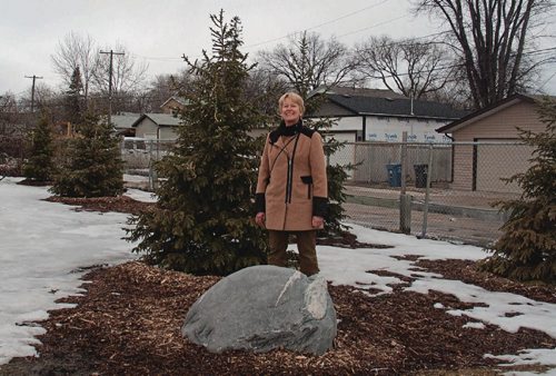 Canstar Community News March 27, 2017 - Christine Frank, chair and committee member of the Wayoata School Greening Project, poses next to a rock from Churchill, Man., and a stand of fir trees that were planted in the fall of 2016 in the first phase of a major greening project the school is undertaking. (SHELDON BIRNIE/CANSTAR/THE HERALD)
