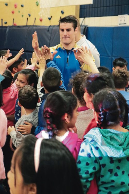 Canstar Community News Winnipeg Blue Bombers linebacker Ian Wild high-fives kids at Ecole Constable Edward Finey at an anti-bullying presentation on April 11, 2017.