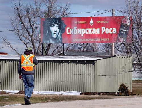 PHIL HOSSACK / WINNIPEG FREE PRESS  -  A Siberia crew member walks past a "Russian Vodka" billboard in Marquette Manitoba Tuesday as the small village hosts the movie set. See Alex Paul story.  -  April 18,  2017