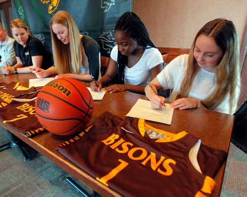 BORIS MINKEVICH / WINNIPEG FREE PRESS
University of Manitoba Bison athletics press conference at Smitty's 2835 Pembina Hwy.  From left, Bison women's basketball head coach Michele Sung (Hynes), Dana Inglis, Bettina Shyllon, and Deidre Bartlett. Here they sign papers to join the Bisons Women's basketball team. April 24, 2017