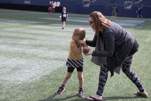 JEN DOERKSEN/WINNIPEG FREE PRESS
Calliope Dickens, 4, and her mom, Winona Dickens, play around with a small football at Investors Group Field during the Bombers Fan Fest this weekend. Young athletes were welcomed to come practice their football skills on the pro field. Saturday, May 6, 2017.