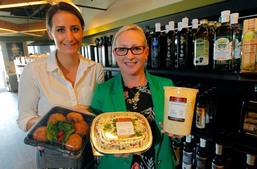 BORIS MINKEVICH / WINNIPEG FREE PRESS
RESTAURANT REVIEW - Agora Market at 1765 Kenaston Blvd.  From left, employees Stephanie Baron and Tanya Hill hold some take out small portion meals that are popular. They stand in front of a wall of olive oil. ALISON GILMOR STORY. May 9, 2017