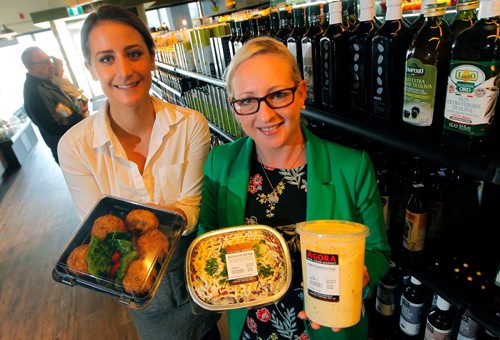 BORIS MINKEVICH / WINNIPEG FREE PRESS
RESTAURANT REVIEW - Agora Market at 1765 Kenaston Blvd.  From left, employees Stephanie Baron and Tanya Hill hold some take out small portion meals that are popular. They stand in front of a wall of olive oil. ALISON GILMOR STORY. May 9, 2017