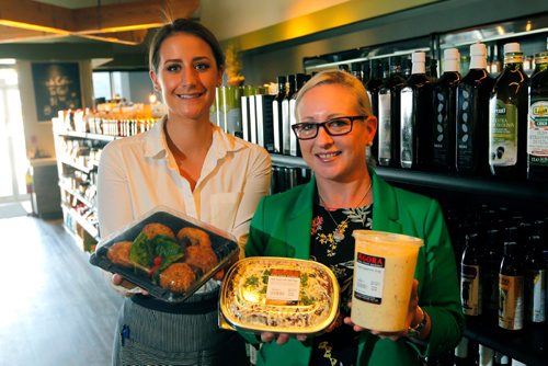 BORIS MINKEVICH / WINNIPEG FREE PRESS
RESTAURANT REVIEW - Agora Market at 1765 Kenaston Blvd.  From left, employees Stephanie Baron and Tanya Hill hold some take out small portion meals that are popular. They stand in front of a wall of olive oil. ALISON GILMOR STORY. May 9, 2017