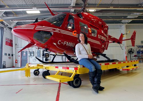 BORIS MINKEVICH / WINNIPEG FREE PRESS
Charity Edwards was transported by STARS in late 2015 after being struck by a vehicle while riding her bicycle in the Grunthal area. She sustained critical life-threatening injuries. She was at the STARS base at the airport today meeting some of the people who were involved in her rescue. Here Charity poses for a photo with one go the choppers. RANDY TURNER STORY. May 16, 2017
