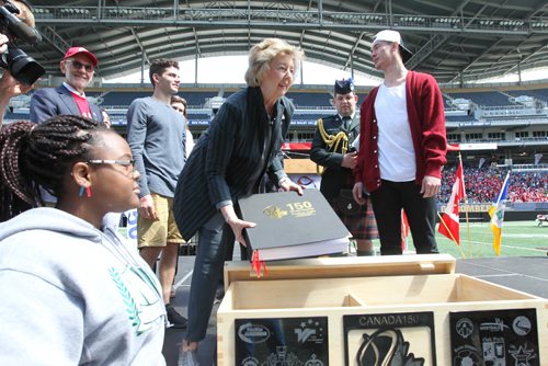 RUTH BONNEVILLE / WINNIPEG FREE PRESS
Manitoba's Lieutenant Governor Janice Filmon places one of several books with signed promises by students to help make Canada a better place into a box on stage at Investors Group Field as part of Canada 150 Project Wednesday.
May 24, 2017