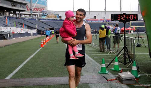 TREVOR HAGAN / WINNIPEG FREE PRESS
Full marathon participant, Murray Carter, carries his 2.5 year old daughter, Lucie, as he crosses the finish line at the 39th Manitoba Marathon, Sunday, June 18, 2017.