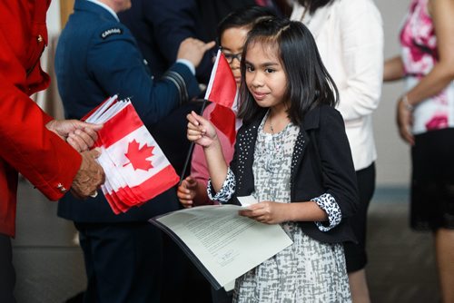 MIKE DEAL / WINNIPEG FREE PRESS
Lucille Jam, 10, receives a flag as she was among the 93 new citizens at a special citizenship ceremony in celebration of Canada's 150th birthday, at the Investors Group Field.
170628 - Wednesday, June 28, 2017.