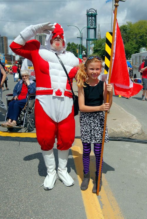 BORIS MINKEVICH / WINNIPEG FREE PRESS
Osborne Village Canada Day street festival was packed with people. From left, Captain Canuck poses with Natasha MacMullin, 8, in the street. July 1, 2017
