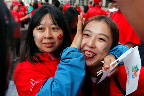 BORIS MINKEVICH / WINNIPEG FREE PRESS
3,600 proud Winnipeggers joined together bright and early at Portage & Main to create a human flag celebrating Canada Day. From left, Candy Tang and Wanruanru Li put on some temporary Canada Day tattoos. July 1, 2017
