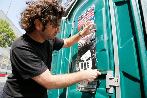 JUSTIN SAMANSKI-LANGILLE / WINNIPEG FREE PRESS
Jon Bennett tapes a poster advertising his Fringe Fest show, "How I Learned to Hug" onto the door of a porta-potty Tuesday. Fringe Fest starts Wednesday and features performances by artists from around the world.
170718 - Tuesday, July 18, 2017.