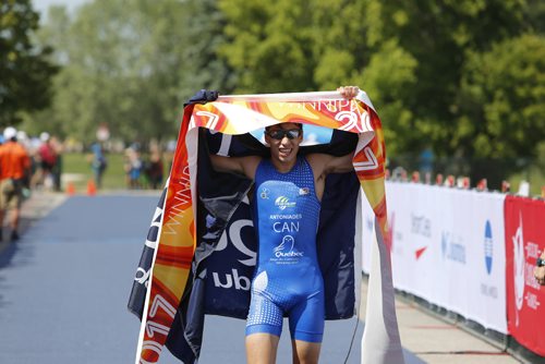 JUSTIN SAMANSKI-LANGILLE / WINNIPEG FREE PRESS
Quebec athlete Paul-Alexandre Pavlos Antoniades crosses the line in first wearing a flag handed from the crowd during Monday's mens triathlon at Birds Hill Park. 
170731 - Monday, July 31, 2017.