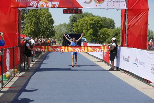 JUSTIN SAMANSKI-LANGILLE / WINNIPEG FREE PRESS
Quebec athlete Paul-Alexandre Pavlos Antoniades crosses the line in first wearing a flag handed from the crowd during Monday's mens triathlon at Birds Hill Park. 
170731 - Monday, July 31, 2017.