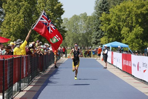 JUSTIN SAMANSKI-LANGILLE / WINNIPEG FREE PRESS
Manitoba athlete Raphael Amour-Lazzari is welcomed to the finish line by a fan waving a Manitoba flag at Monday's mens triathlon at Birds Hill Park.
170731 - Monday, July 31, 2017.