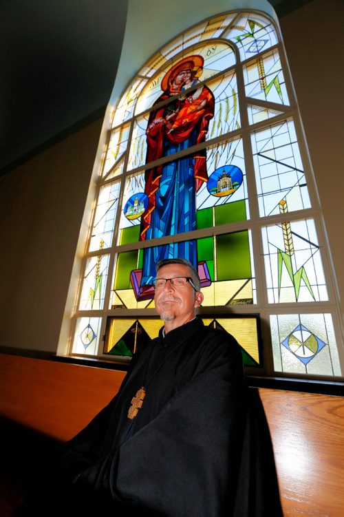 JUSTIN SAMANSKI-LANGILLE / WINNIPEG FREE PRESS
Rev. Eugene Maximiuk of Holy Trinity Ukrainian Orthodox Metropolitan Cathedral poses in front of one of the cathedral's newly restored stained glass windows Friday. 
170804 - Friday, August 04, 2017.