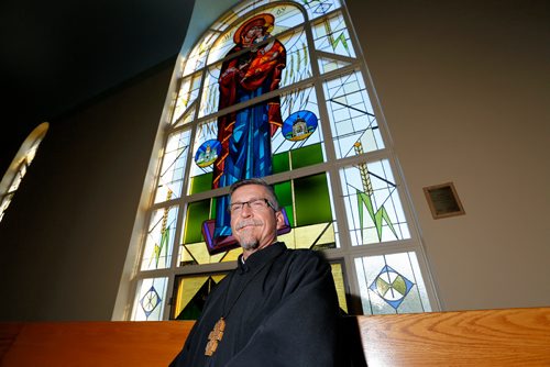 JUSTIN SAMANSKI-LANGILLE / WINNIPEG FREE PRESS
Rev. Eugene Maximiuk of Holy Trinity Ukrainian Orthodox Metropolitan Cathedral poses in front of one of the cathedral's newly restored stained glass windows Friday. 
170804 - Friday, August 04, 2017.