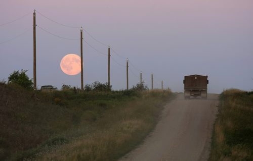 Brandon Sun A grain truck travels along a sideroad south of Forrest, Man., as a harvest moon climb above the horizon on Tuesday evening. FOR C1 HOLD (Bruce Bumstead/Brandon Sun)