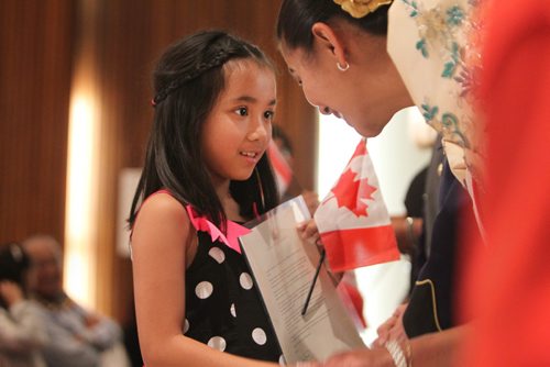 RUTH BONNEVILLE / WINNIPEG FREE PRESS

Young Charley Yaj Garcia Uy smiles as she holds her new Canadian citizenship certificate while she shakes Sheryl Vasquez hand,  adult ambassador for Folklorama's  Pearl of the Orient Philippine Pavilion, at a citizenship ceremony Friday.  The special ceremony was  held at the Philippine Folklorama venue as part of Canada 150 celebrations which welcomed 50 new citizens. 
Standup photo 

Aug 11,, 2017