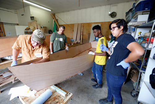 JUSTIN SAMANSKI-LANGILLE / WINNIPEG FREE PRESS
Instructor Warren Bend (left) shows Jaden Cassidy, Yined Yosef and Deanna Hill how to apply epoxy to the seams of the wooden boat they are building Tuesday at FortWhyte Farms. The youth are working on the farm as part of an employment program organized by the farm. Participants are paid farm hands for the summer and will rotate through kitchen, carpentry and farming shifts.
170815 - Tuesday, August 15, 2017.