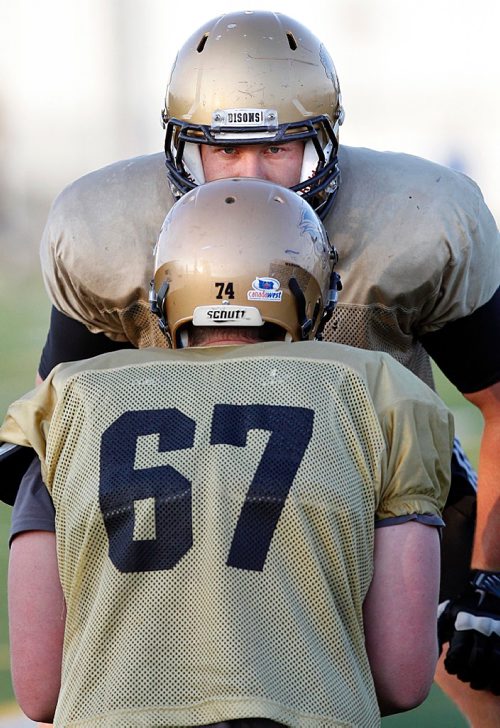 PHIL HOSSACK / WINNIPEG FREE PRESS - Tom Clarkson peers over the helmet of his brother Matt as the linemen brothers took part in a Bison workout Wednesday.  - . See Taylor's story.  - August 16, 2017