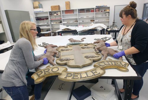 JOE BRYKSA / WINNIPEG FREE PRESS Manitoba Museums Carolyn Sirett, Conservator , left and Cortney Pachet, Collections Registration Associate - Human History unpack donated  HBC Coat of Arms from exterior Kamloops, BC store.  Aug 15, 2017 -( See Melissa Martins 49.8 story  story)