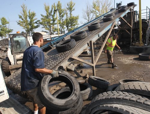JOE BRYKSA / WINNIPEG FREE PRESS Reliable Tire Recycling employee Safy Dost, left, loads recycled tires on to conveyer belt heading for the shredder.Aug 18, 2017 -( See Murrays  story)