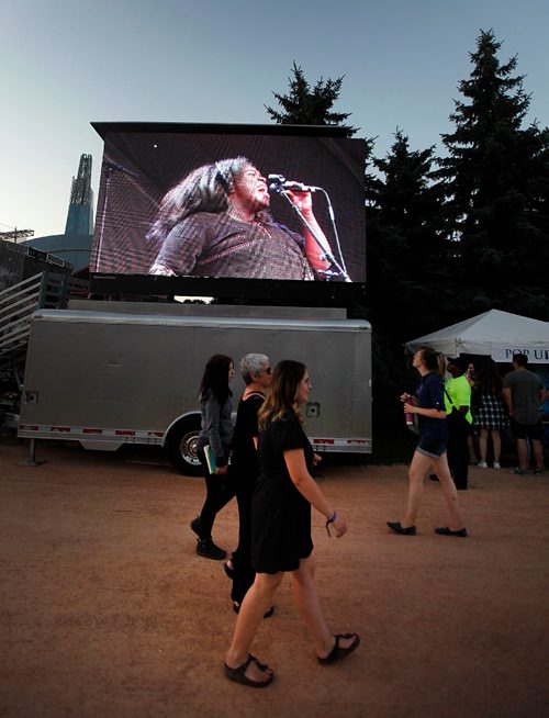 PHIL HOSSACK / WINNIPEG FREE PRESS  - Interstellar Rodeo fans stroll past a monitor image projecting Yola Carter on her first Canadian tour stop performing at Interstellar Rodeo's opener Friday night for the weekend festival at the Forks. - August 17, 2017