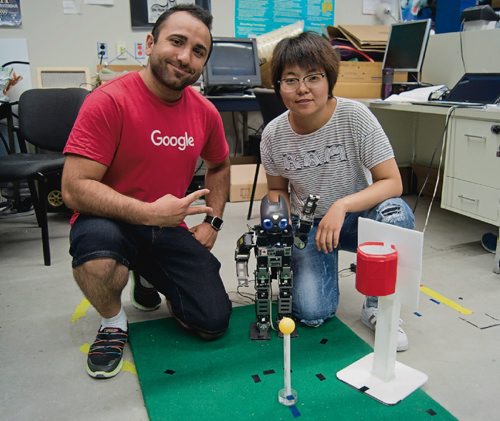 Canstar Community News Aug. 8, 2017 - From left, Amir Hossein Memar and Qiuting Gong of the University of Manitobas Autonomous Agents Laboratory pose with Jennifer the humanoid robot. It will be competing in basketball in the HuroCup from Aug. 23 to 27.  (DANIELLE DA SILVA/CANSTAR/SOUWESTER)