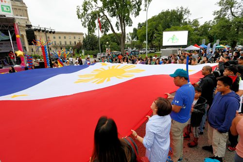 JUSTIN SAMANSKI-LANGILLE / WINNIPEG FREE PRESS
Spectators and organizers join forces to hold up a giant Filipino flag Saturday during the Filipino Street Festival.
170826 - Saturday, August 26, 2017.