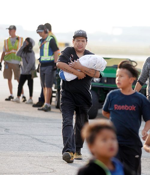 PHIL HOSSACK / WINNIPEG FREE PRESS  - A Northern Manitoba fire evacuee carrying a baby steps off of a Canadian Forces C130 Herculese transport arrives at James Richardson International Airport in Winnipeg Ferrying northern Manitoba fire evacuees south to shelter.- August 30, 2017