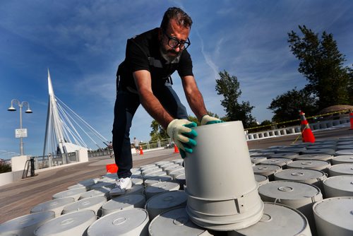 JOHN WOODS / WINNIPEG FREE PRESS
Mexican architect Fermin Espinosa adds a bucket to his international art exhibit One Bucket At A Time on the Esplanade Riel in Winnipeg Monday, September 11, 2017. Espinosa's architecture firm Factor Eficiencia has partnered with 5468796 Architecture and Studio NYL Structural Engineers to bring his public installation that weaves together thousands of common 5-gallon painters buckets to form two giant waves to Winnipeg. Visitors to the installation are invited to fill the wave of buckets through individual donations of $20. Arriving in Canada empty, each bucket used to construct the project will leave for Mexico filled with Canadian generosity, with all proceeds to be given to Ayuda y Solidaridad con las Niñas de la Calle, a Mexican orphanage for at-risk girls and young women located in Mexico City. Donations can be made through www.5468796.ca.