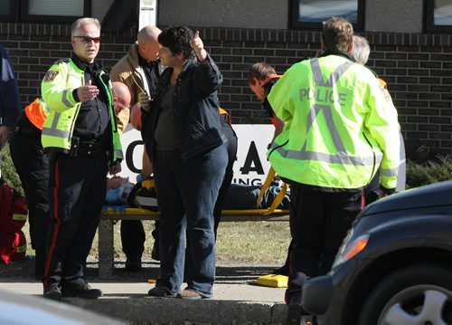 Brandon Sun  Constable Shane Stephenson takes a statement from a motorist as emergency works tend to a pedestrian which was struck at the crosswalk at 18th Street and Louise Avenue on Thursday afternoon. The pedestrian was taken to hospital. (Bruce Bumstead/Brandon Sun)