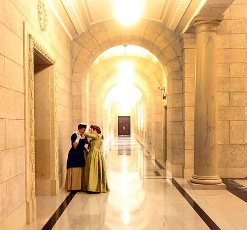 PHIL HOSSACK / WINNIPEG FREE PRESS  -   Judy Blanchette (left) pauses to let Sandra Stampe-Sobering adjust her cap as the pair make their way down legislative hallways Tuesday, en-route to a plaque re-dedication ceremony honoring the United Empire Loyalists  - Sept 19 2017