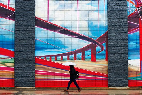 JOHN WOODS / WINNIPEG FREE PRESS
A pedestrian takes shelter from the rain as he walks past a Sherbrook Street mural by Michel Saint Hilaire Tuesday, September 26, 2017. Temperatures and sunshine should increase for the rest of the week,