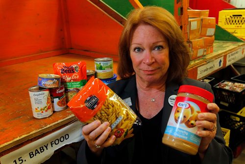 BORIS MINKEVICH / WINNIPEG FREE PRESS
Winnipeg Harvest executive director Kate Brenner poses with some of the top 10 thing people need at the food bank. Sept. 27, 2017