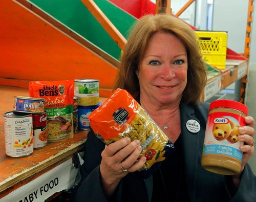 BORIS MINKEVICH / WINNIPEG FREE PRESS
Winnipeg Harvest executive director Kate Brenner poses with some of the top 10 thing people need at the food bank. Sept. 27, 2017