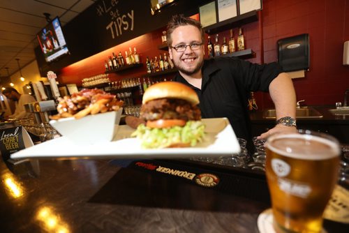 TREVOR HAGAN / WINNIPEG FREE PRESS
Josh Nesojednik, owner, holding the Bacon Poutine and the Winnipegger Burger at the Tipsy Cow, restaurant review, Friday, October 6, 2017.